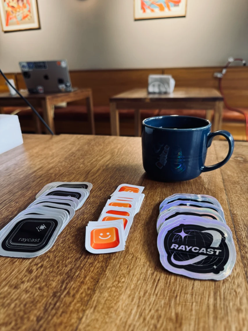 Raycast stickers with a cup of coffee on a table